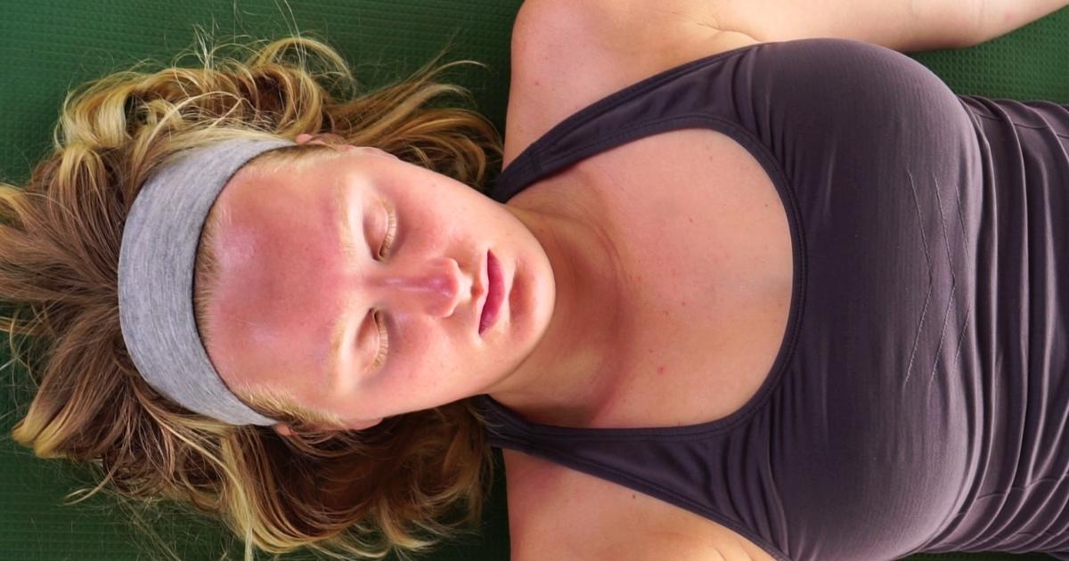 Woman practicing Yoga Nidra lying in Shavasana during online teacher training